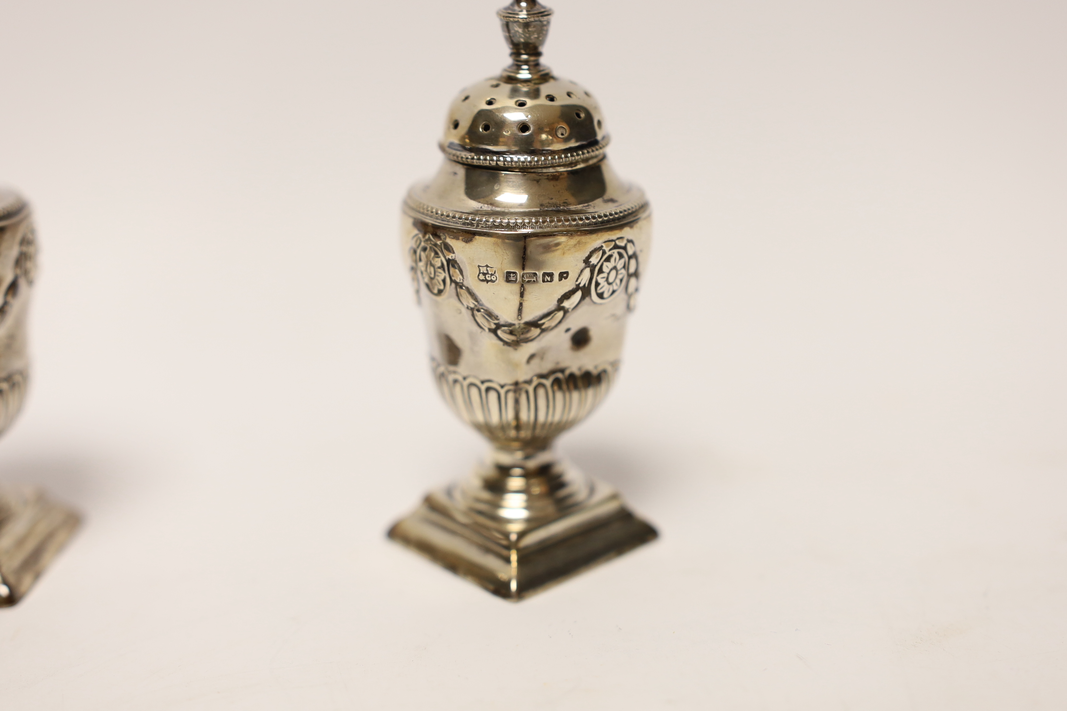A pair of Victorian silver urn shaped pedestal pepperettes, Henry Wilkinson & Co Ltd, Sheffield, 1880, 83mm.